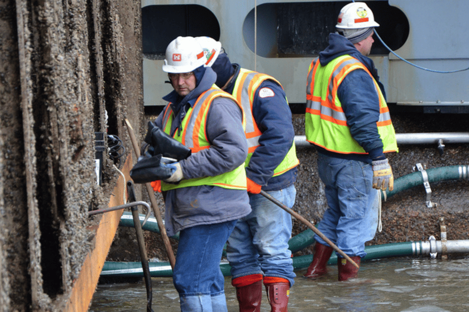 USACE operations employees scrape zebra mussels off the lock wall. The U.S. Army Corps of Engineers St. Paul District dewatered Lock and Dam 7, located near La Crescent, Minn., to do major renovation and rehabilitation work. (U.S. Army Corps of Engineers photo by Shannon Bauer)